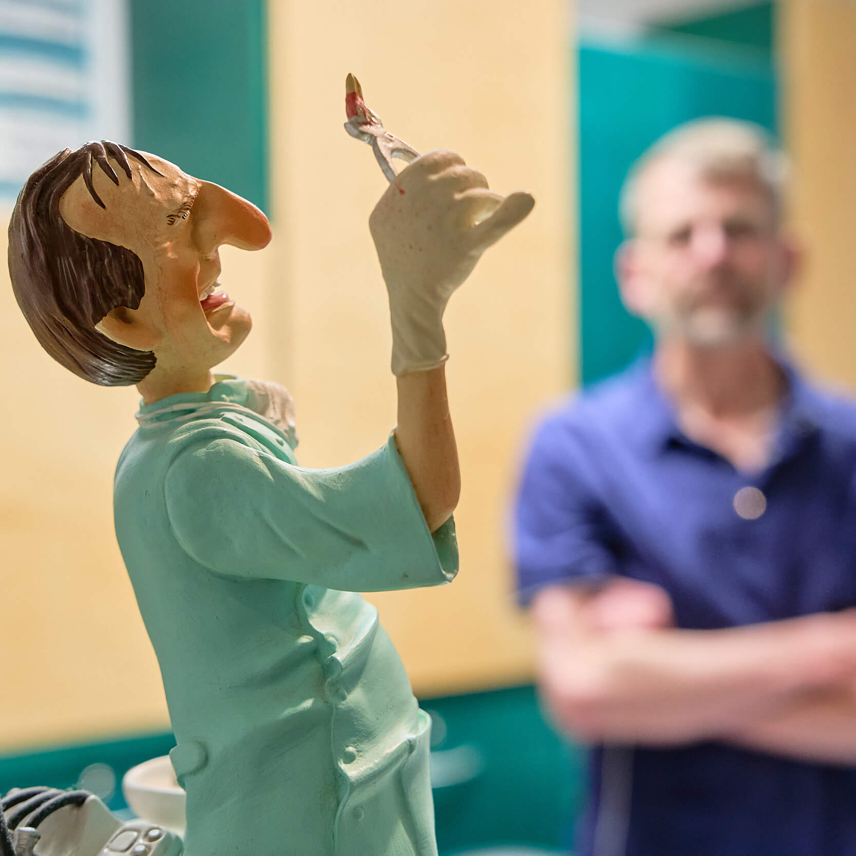 Figur eines Zahnarztes mit Dr. Robin Roenspies unscharf im Hintergrund